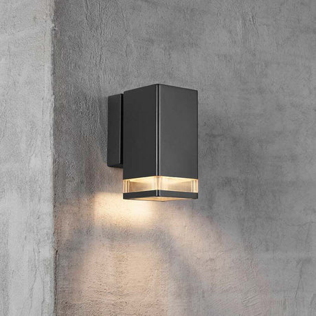 Außen-Wandlampe Elm IP44 Schwarz, Klar an einer Wand montiert mit warmem Licht.