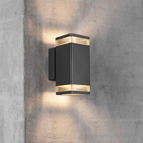 Außen-Wandleuchte Elm IP44 Schwarz, Klar an einer Betonwand, modernes Design mit warmem Licht.