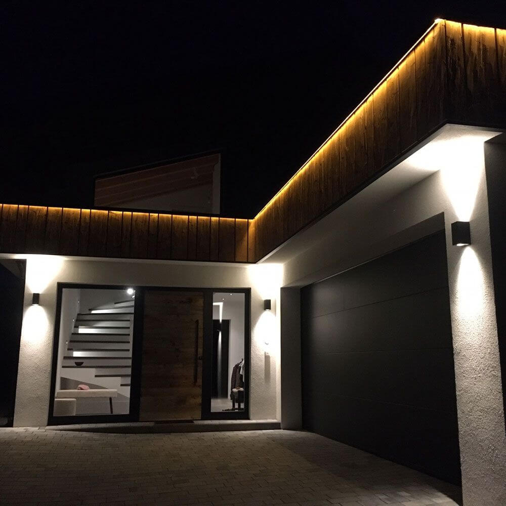 Außenwandlampe Canto Maxi 2 IP44 Seaside Schwarz beleuchtet Eingangsbereich eines modernen Hauses.