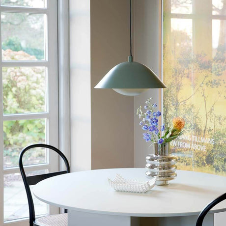 Freya Hängeleuchte über einem Esstisch mit Blumenvasen im skandinavischen Design.