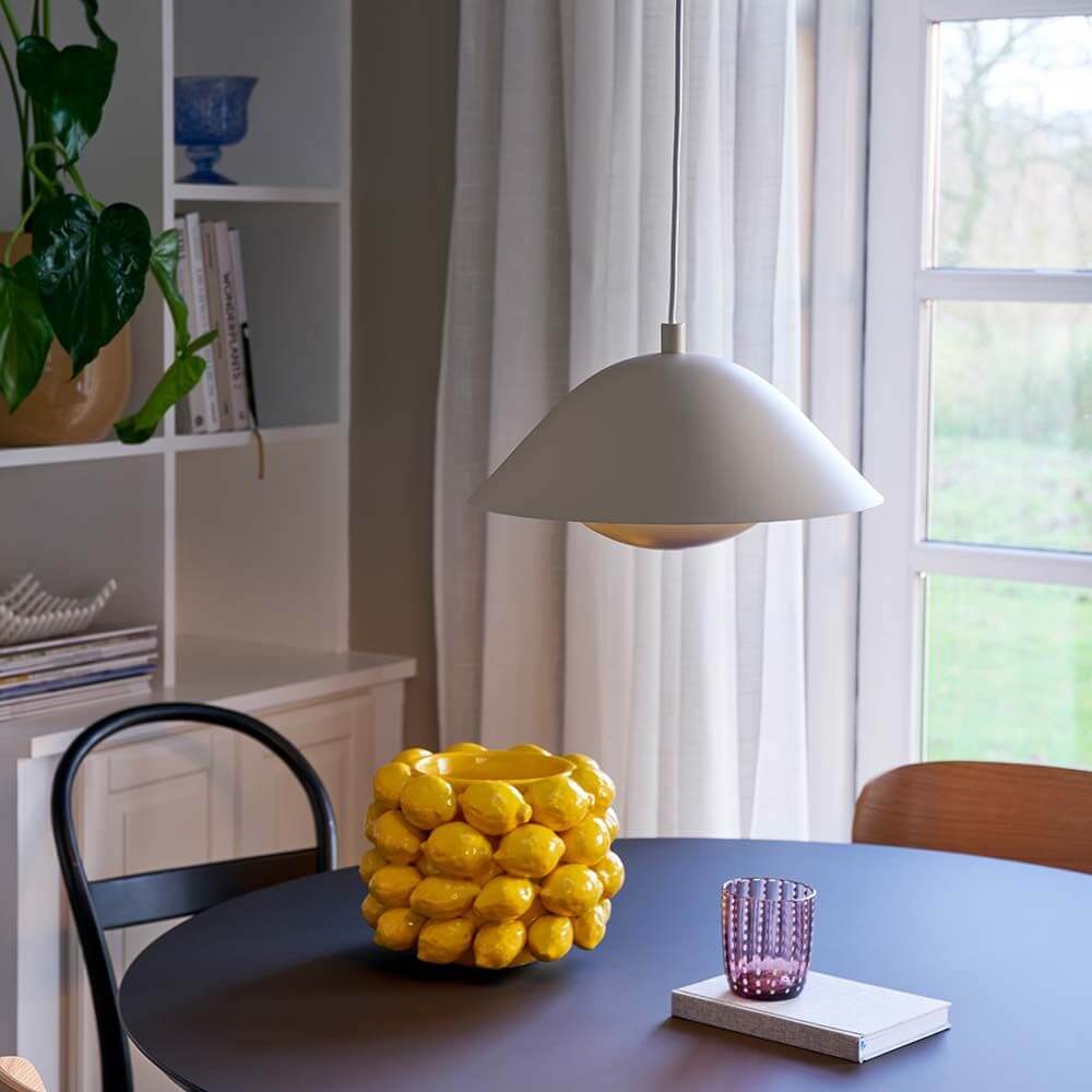Freya Hängeleuchte über einem Esstisch mit gelben Zitronen und buntem Glas, skandinavisches Design.