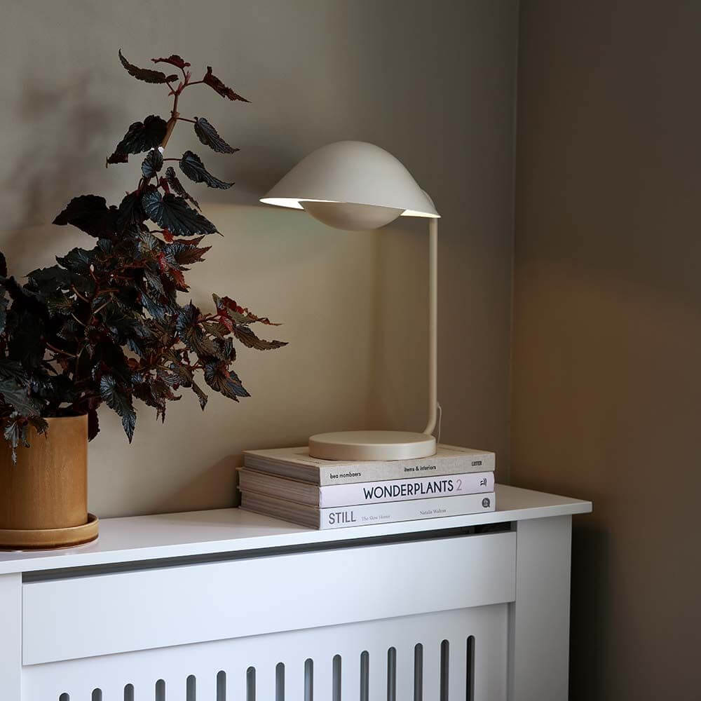 Freya Tischleuchte auf einem Tisch mit Pflanzen und Büchern, skandinavisches Design und elegante Silhouette.