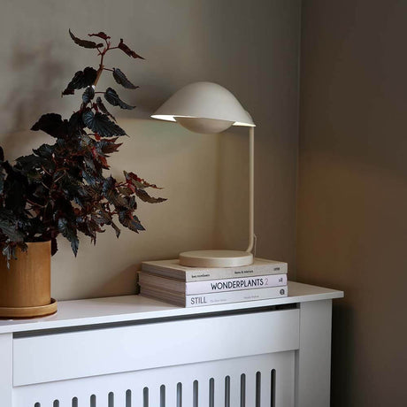 Lampe de table Freya sur une table avec des plantes et des livres, design scandinave et silhouette élégante.