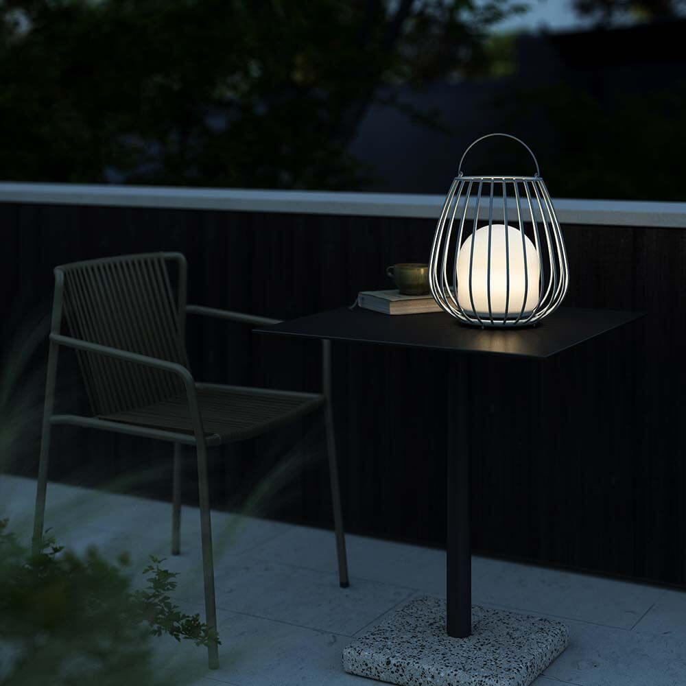 Jim To Go LED Akku Bodenleuchte auf Tisch, stilvolles Design für Terrasse oder Garten, stimmungsvolle Beleuchtung.