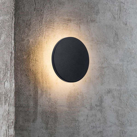 LED Udendørs væglampe Artego IP54 Sort på betonvæg med varmt lys.