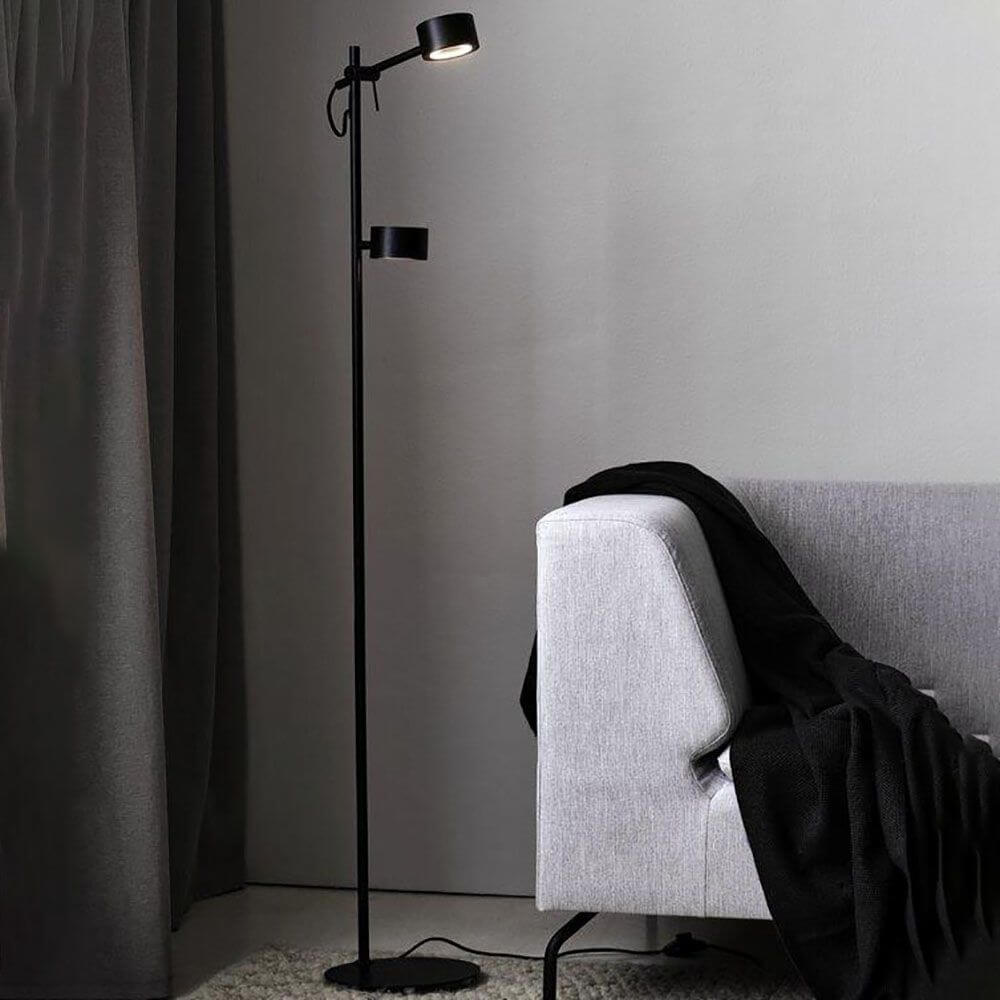 LED Stehleuchte Clyde 2-flammig Schwarz in modernem Wohnambiente neben Sofa mit Decke.