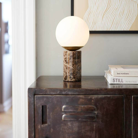 Lilly marble table lamp on a table, elegant design with a marble base and rounded glass dome.