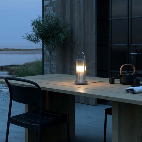 Lanterne de table Linton sur une table à l’extérieur, présentée à la tombée de la nuit.