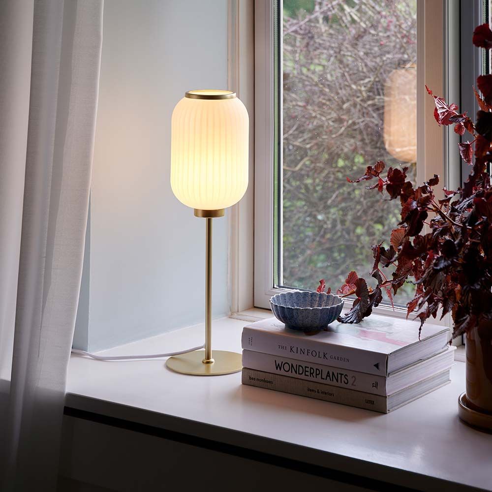Milford Glas Tischlampe Messing auf Fensterbank, elegante Beleuchtung mit opalweißem Glas und Messing-Sockel.