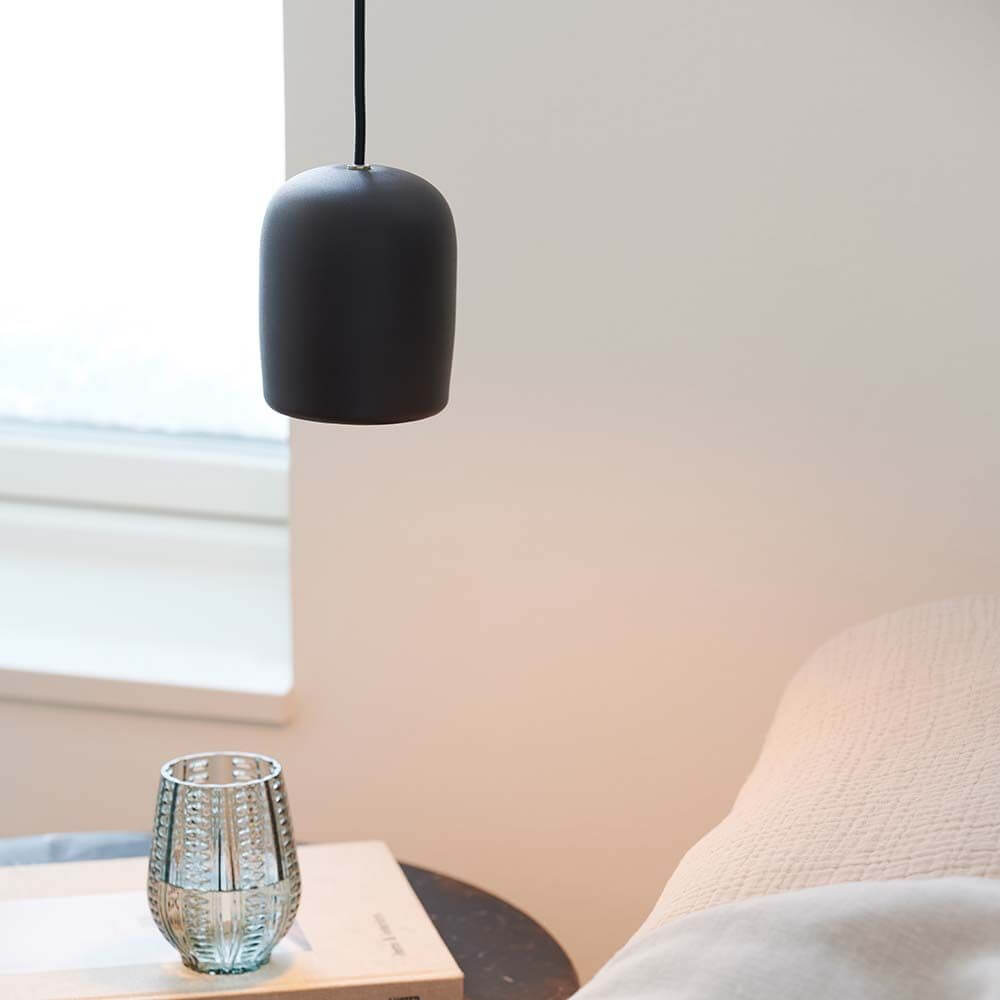 Notti Pendelleuchte in modernem skandinavischen Design über einem Tisch mit Glas und Buch.