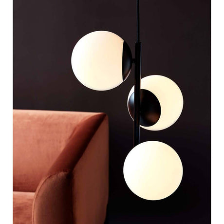 Pendelleuchte Lilly Schwarz, Opalweiß über einem stilvollen Sofa, kombiniert Eleganz und modernes Design.
