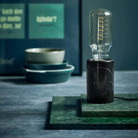 Siv Marble Table Lamp Black on a green background with decorative light.