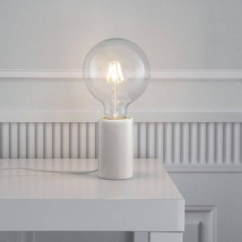 Tischleuchte Siv mit weißen Marmor – moderne Designerlampe auf einem Tisch. Warmes Licht, stilvolles Design.