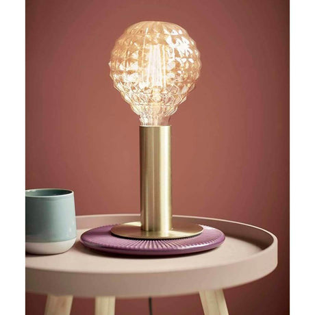 Lampe de table Dean en laiton sur une table d'appoint avec une ampoule moderne.