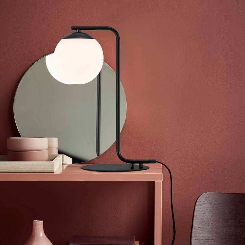 Tischlampe Grant Schwarz, Opal Weiß auf einem Tisch mit Spiegel und Dekorationsobjekten.