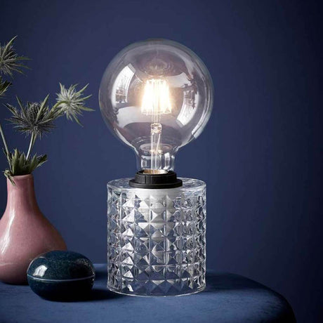 Tischlampe Hollywood Klar mit glänzendem Glaskörper und stilvollem Lampenschirm auf einem Tisch.