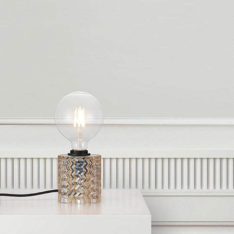 Lampe de table Hollywood Ambre sur table avec globe en verre et socle décoratif.