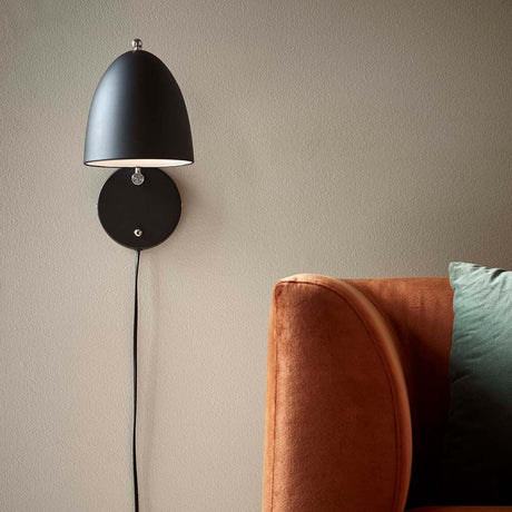 Wandlampe Alexander Schwarz an einer Wand über einem bequemen Sofa, elegantes und modernes Design.