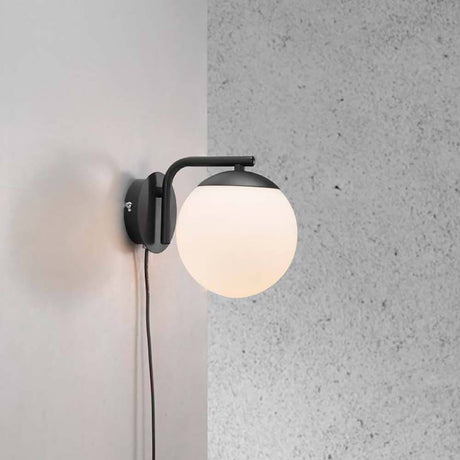Wall light Grant Black, Opal White mounted on a wall with an elegant glass surface.