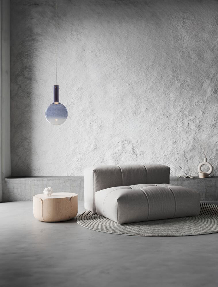 Moderne Nostos Pendelleuchte in einem stilvollen Raum mit grauer Couch und runder Teppich.