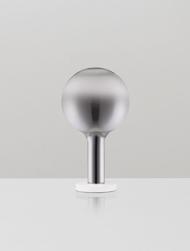 Nostos LED Tischleuchte Ø 20cm 3000K auf einem Tisch mit modernem Design und eleganter Metalloberfläche.