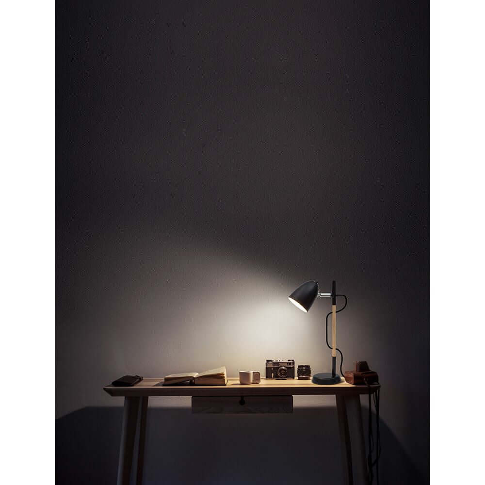 Alina Tischlampe Metall Holz auf einem Tisch, blendet sanft Licht auf Notizbuch und Kamera.