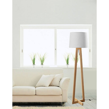 Lampadaire Alma en bois naturel, blanc, dans un salon moderne à côté du canapé et de la fenêtre.