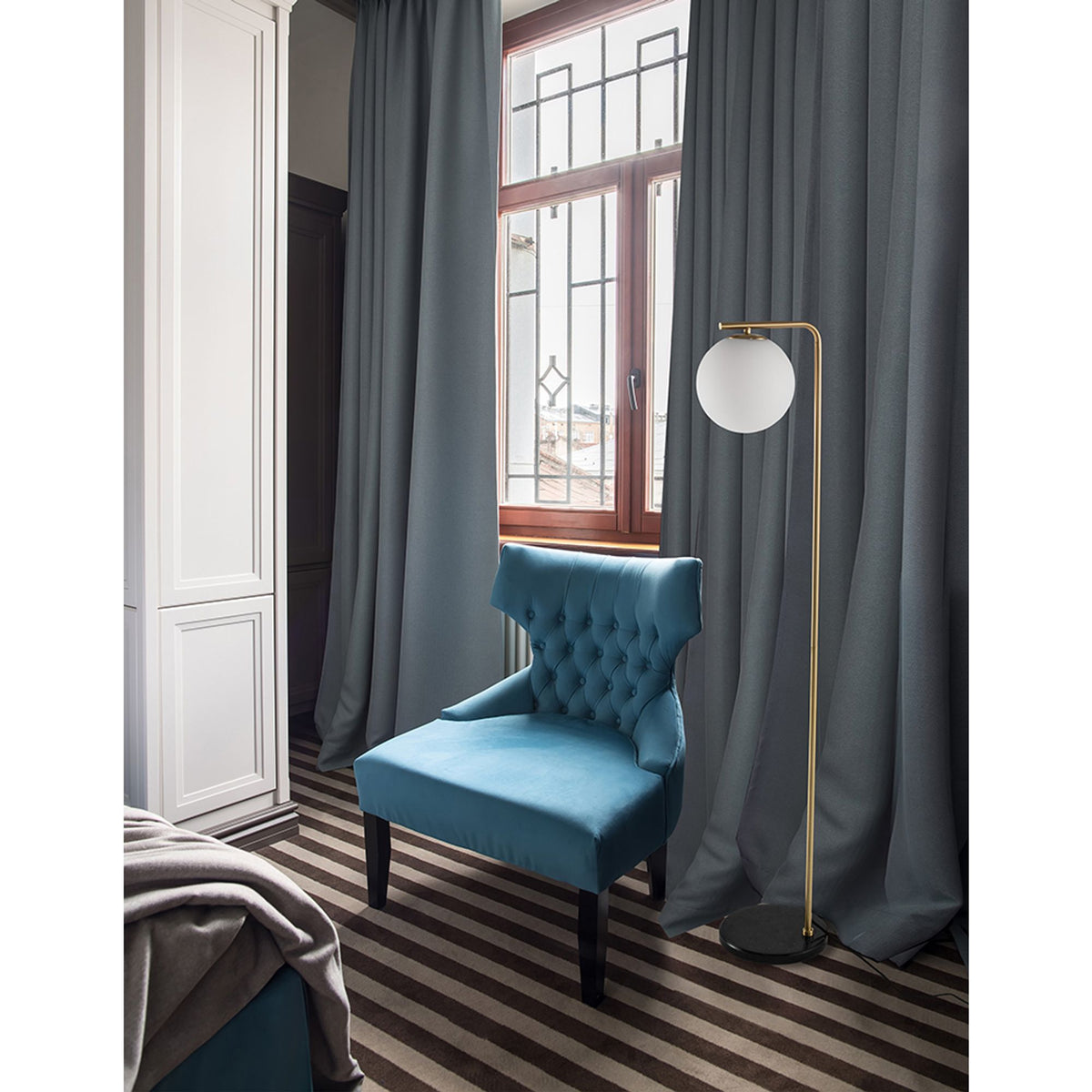 Nova Luce Alvarez floor lamp with golden frame and white globe shade, marble base, next to blue armchair