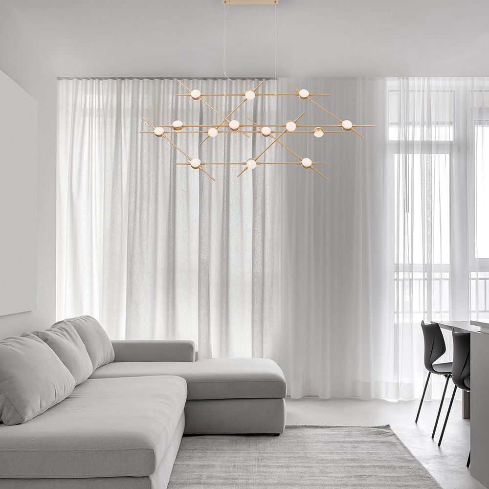 Moderne Atomo LED Hängeleuchte in Goldfarben über einem grauen Sofa in einem hellen, stilvollen Raum.