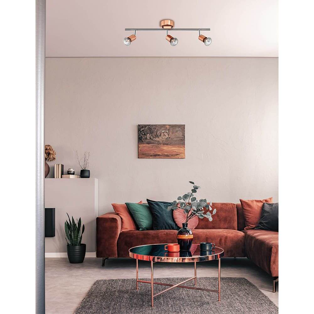 Base Balkenstrahler Metall 3-flammig im modernen Wohnzimmer über einem Kaffeetisch mit braunem Sofa.
