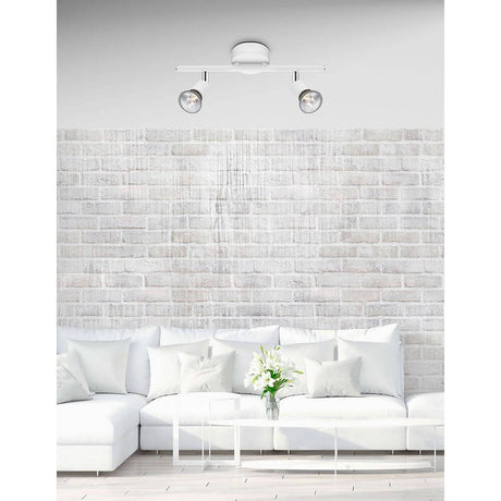 Base 2-light bar spotlight above a modern sofa in a bright living room.
