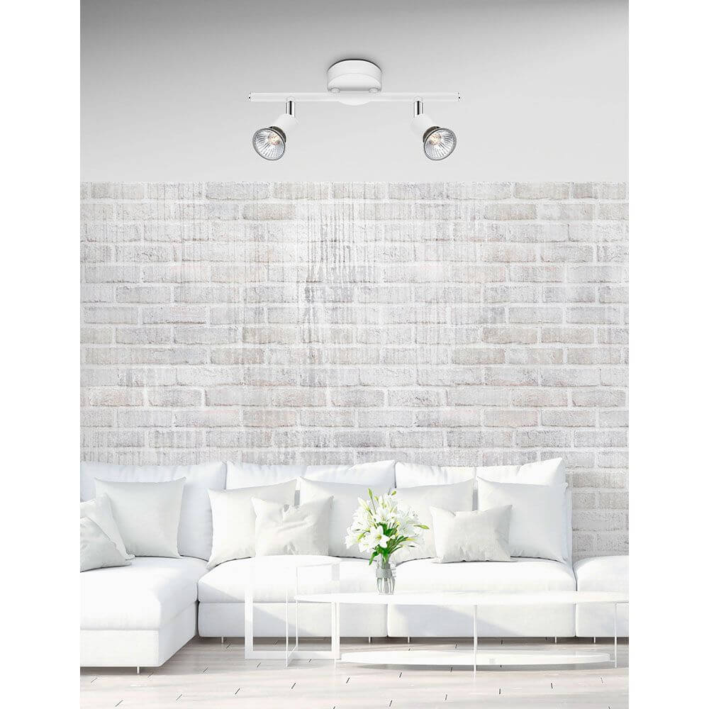 Base Balkenstrahler 2-flammig über einem modernen Sofa in einem hellen Wohnzimmer.