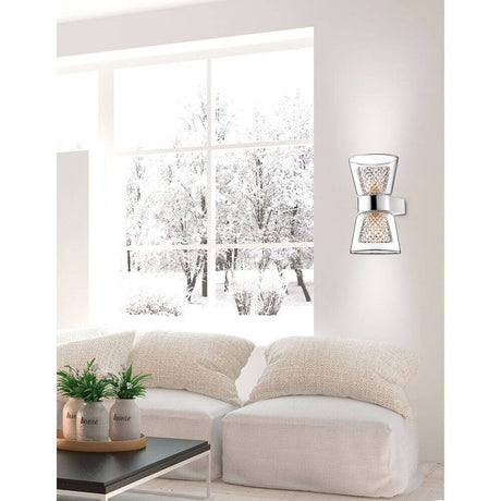 Boccale Glas-Wandlampe Chrom, Klar an einer Wand neben einem gemütlichen Sofa mit Winterblick.