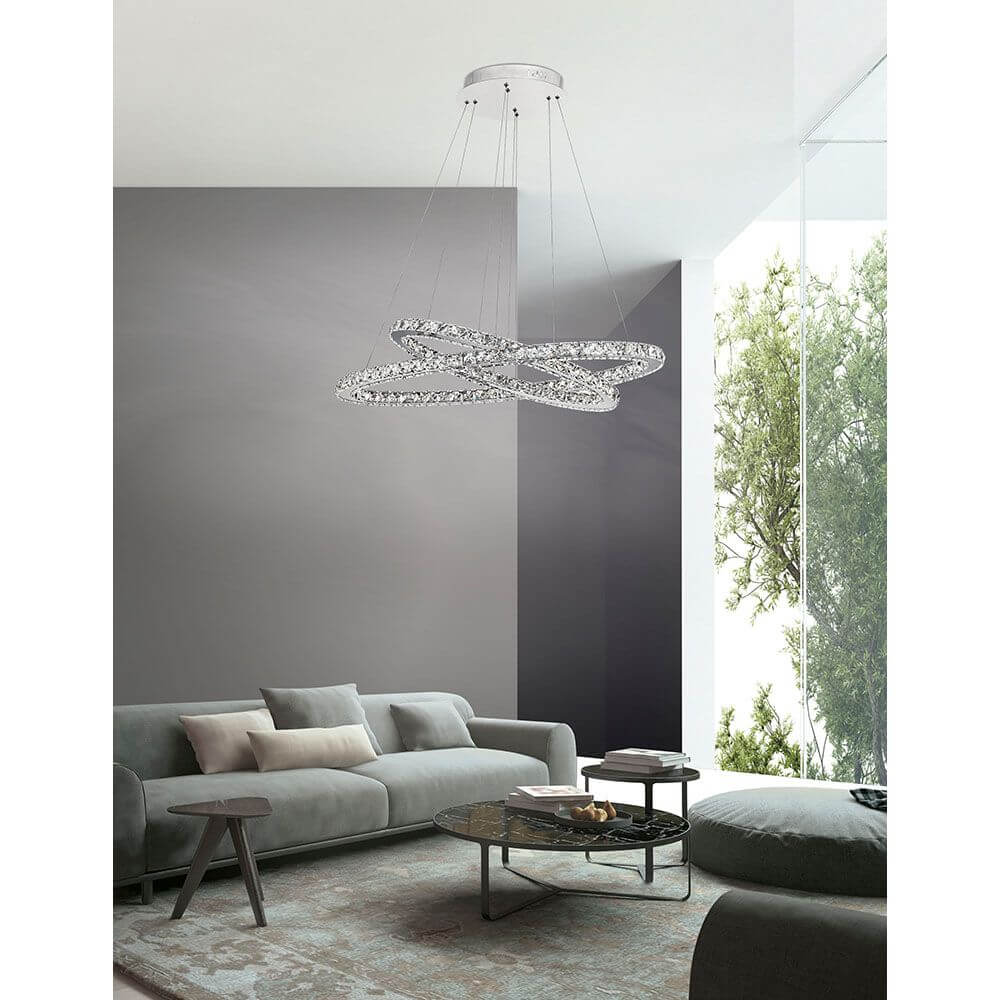 Celine LED Kristall-Hängeleuchte Glas Chrom über modernem Wohnzimmer mit Sofa und Fenster