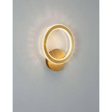 Cilion LED brass wall light, gold, with modern design and soft light on a gray background.