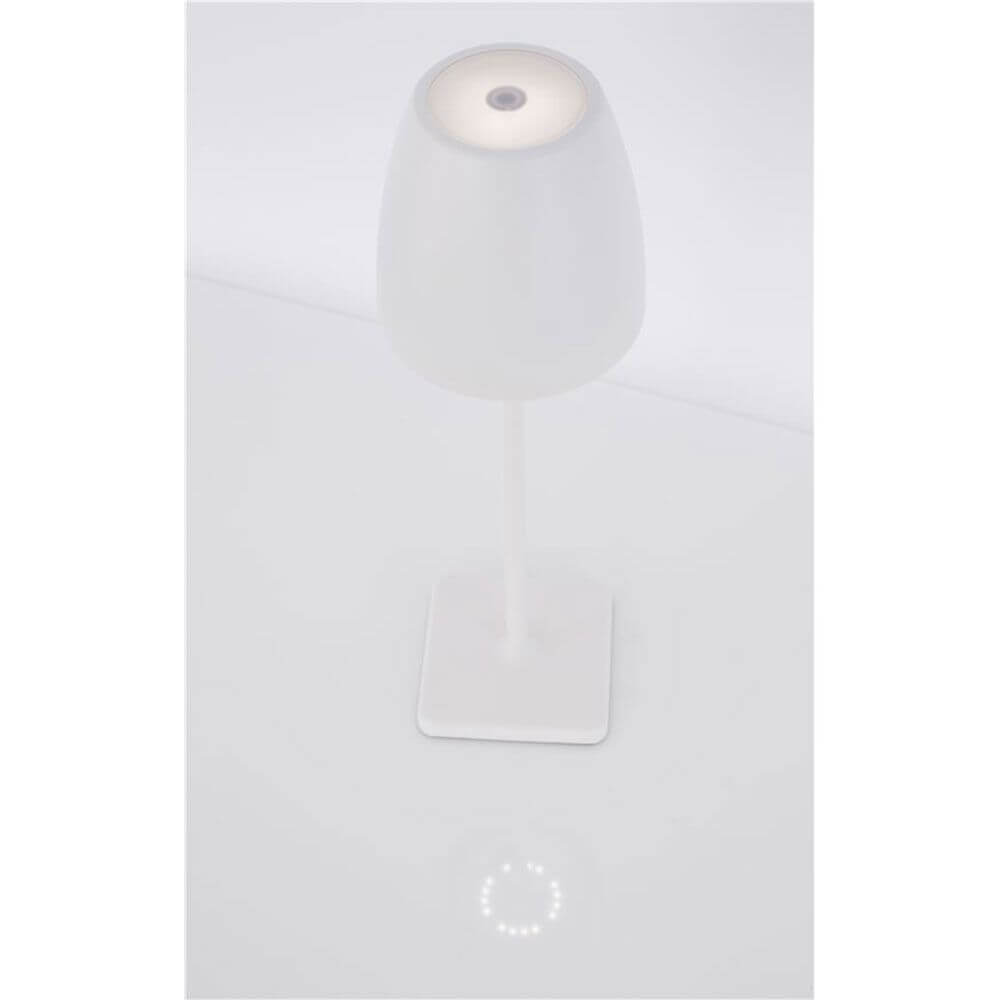 Colt Outdoor-Tischleuchte Akku IP44 Weiß auf einem weißen Tisch, minimalistisches Design mit sanftem Licht.