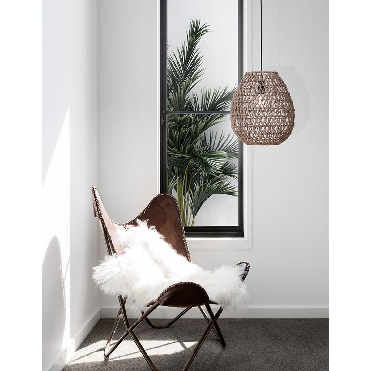 Suspension Nova Luce Griffin en moka, luminaire suspendu tressé au-dessus d’un fauteuil en vue d’ambiance