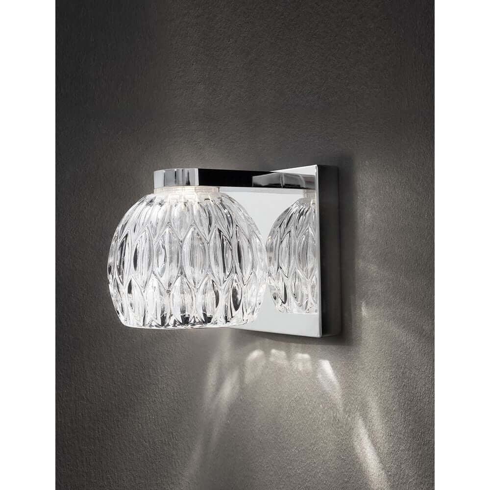 Lara Wandlampe Glas Chrom an einer Wand montiert mit eleganter Glas- und Chrom-Optik.