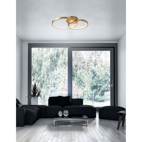 Leon LED plafonnier en métal doré dans un salon moderne avec canapé noir et grandes fenêtres.