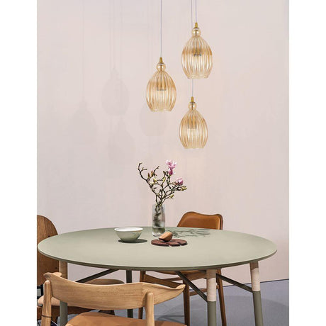 Nova Luce Lingua Hängelampe 3-flammig Glas Champagner über einem runden Tisch mit Blumen.