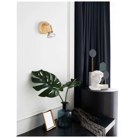 Lup Spot wall lamp metal on a wall with stylish decor and plant arrangement.