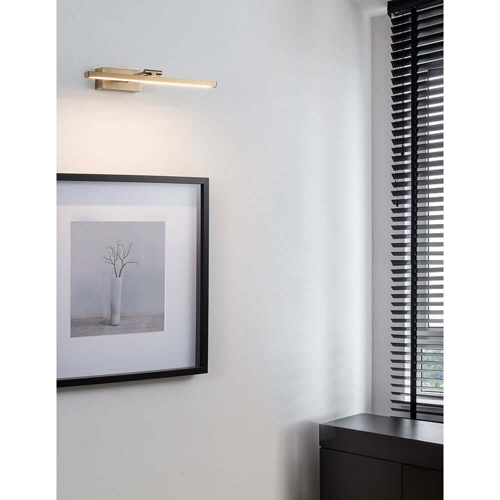 Marnell LED Wandlampe Antik-Messing an einer Wand in einem modernen Raum mit Kunstwerk.