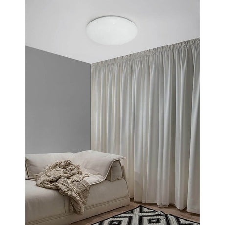 Minori Deckenlampe Ø 40cm Glas Weiß installiert in einem modernen Schlafzimmer mit Vorhängen.
