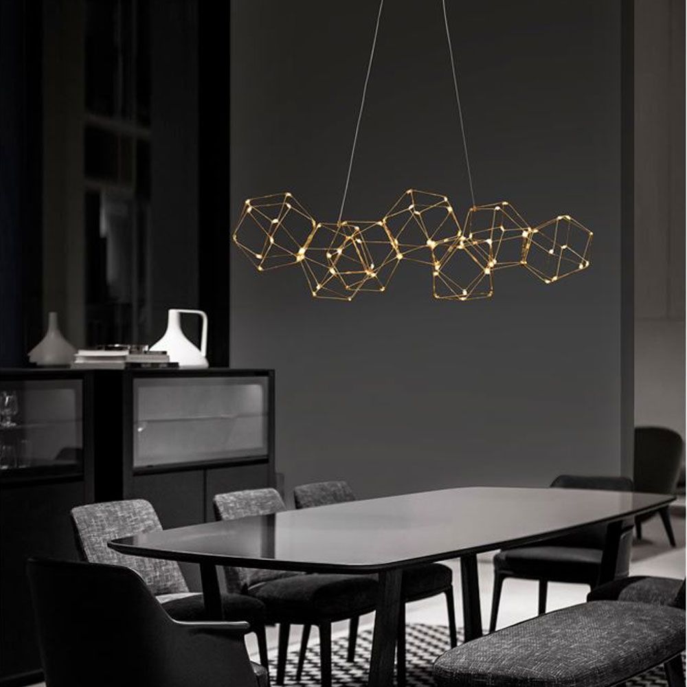 Moderne Nebula LED Pendellampe in Gold über einem eleganten Esstisch mit Stühlen.