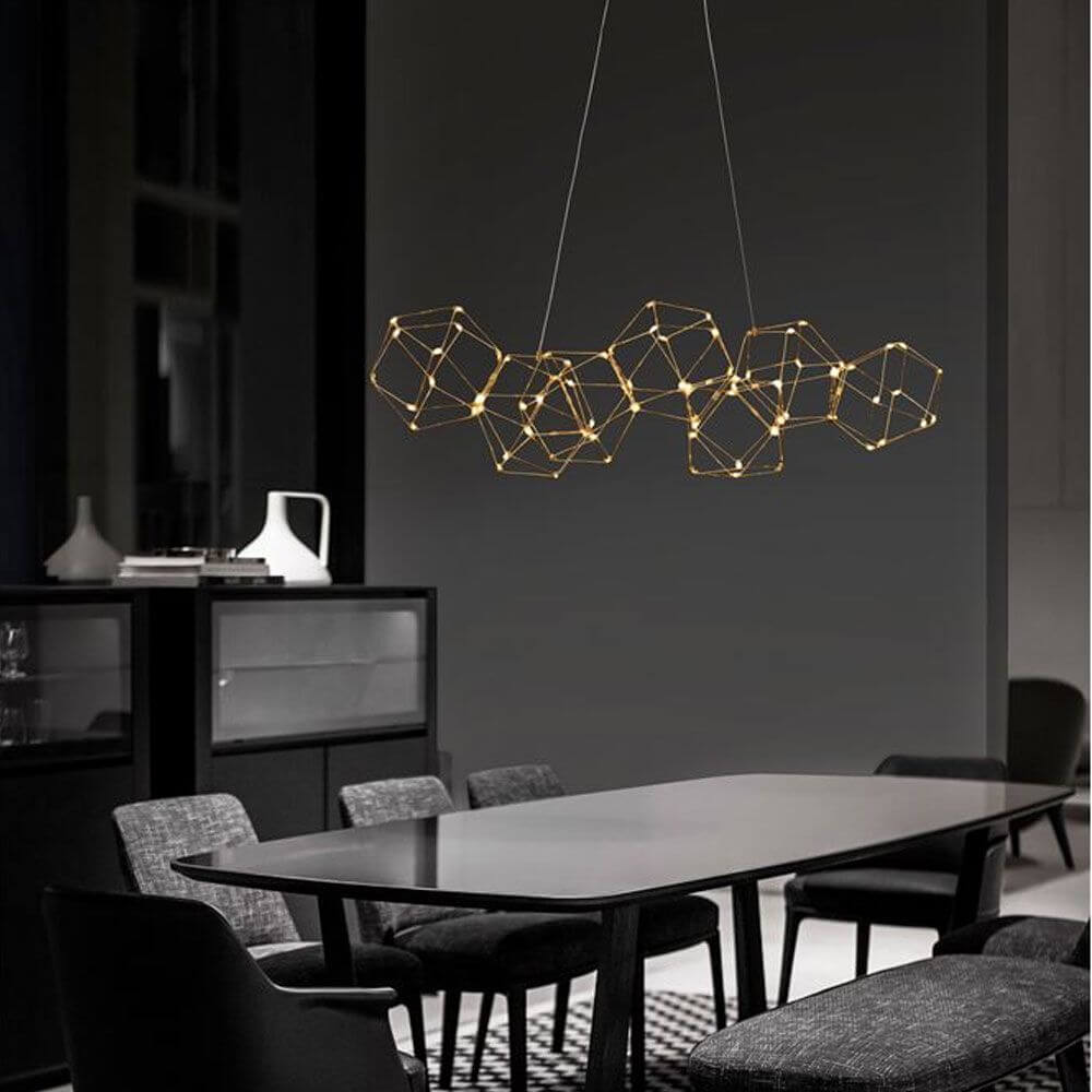 Nebula LED Würfel Pendellampe Goldfarben über einem eleganten Esstisch in modernen Innenräumen.