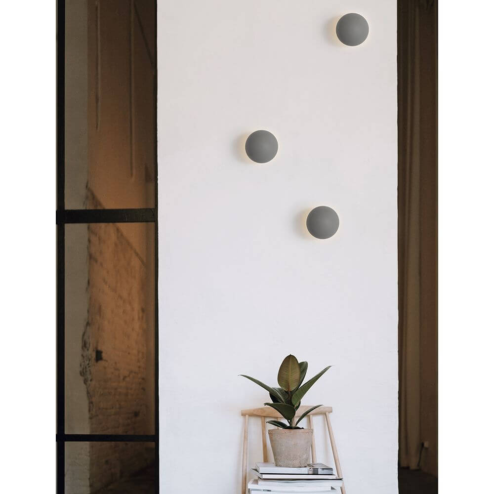 Netune LED Wandleuchte Ø 11cm an einer Wand, modernes Design in Grau und Weiß, ideal für verschiedene Räume.