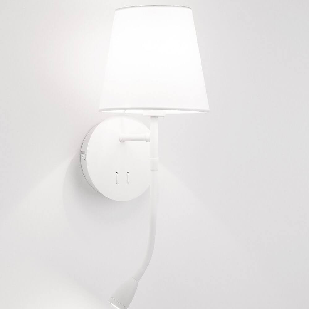 Nia Wandleuchte Metall mit LED Leselicht an einer weißen Wand montiert, mit hellem Stoffschirm.