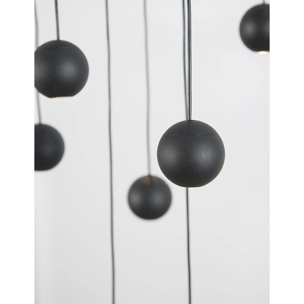 Nocci LED Hängelampe Kugel-Aufhängung Schwarz mit mehreren hängenden schwarzen Kugeln an schwarzen Kabeln.