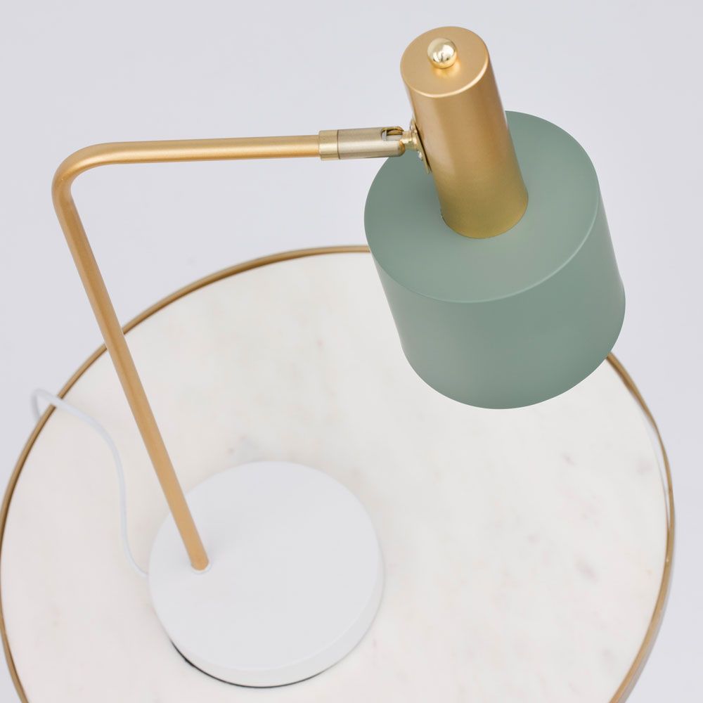 Goldfarbene Skandi Tischleuchte mit grünem Lampenschirm auf einem weißen Tisch. Modernes nordisches Design.