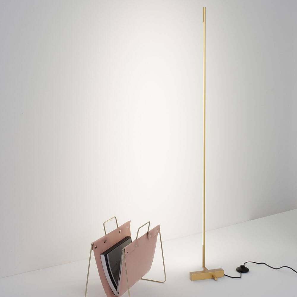 Raccio LED Stehlampe 140cm Gold neben einem Zeitungsständer in einem modernen Wohnraum